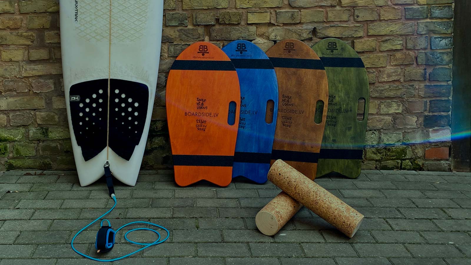 Surfboard next to brick wall. Balance boards in Various colors. A balance board is a small but brutally effective trainer. It doesn’t shout, it doesn’t need much space