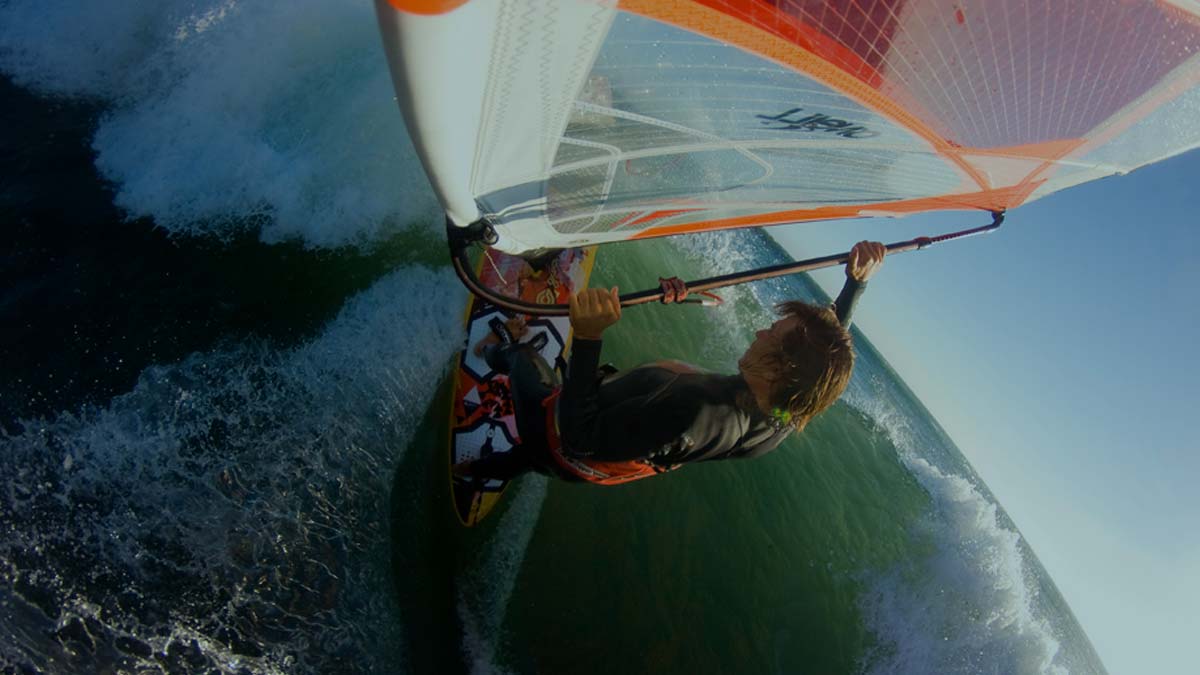 Windsurfer ridi g a wave. Onboard camera angle. Windsurfing harness.