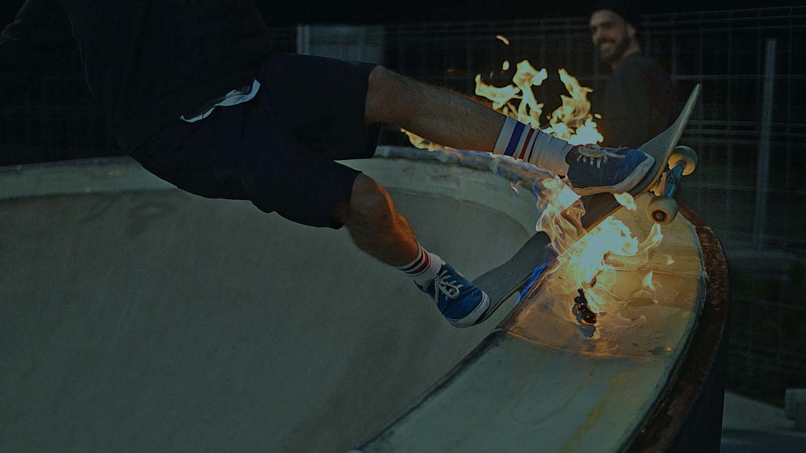 Skateboarder riding a pool lite on fire.
