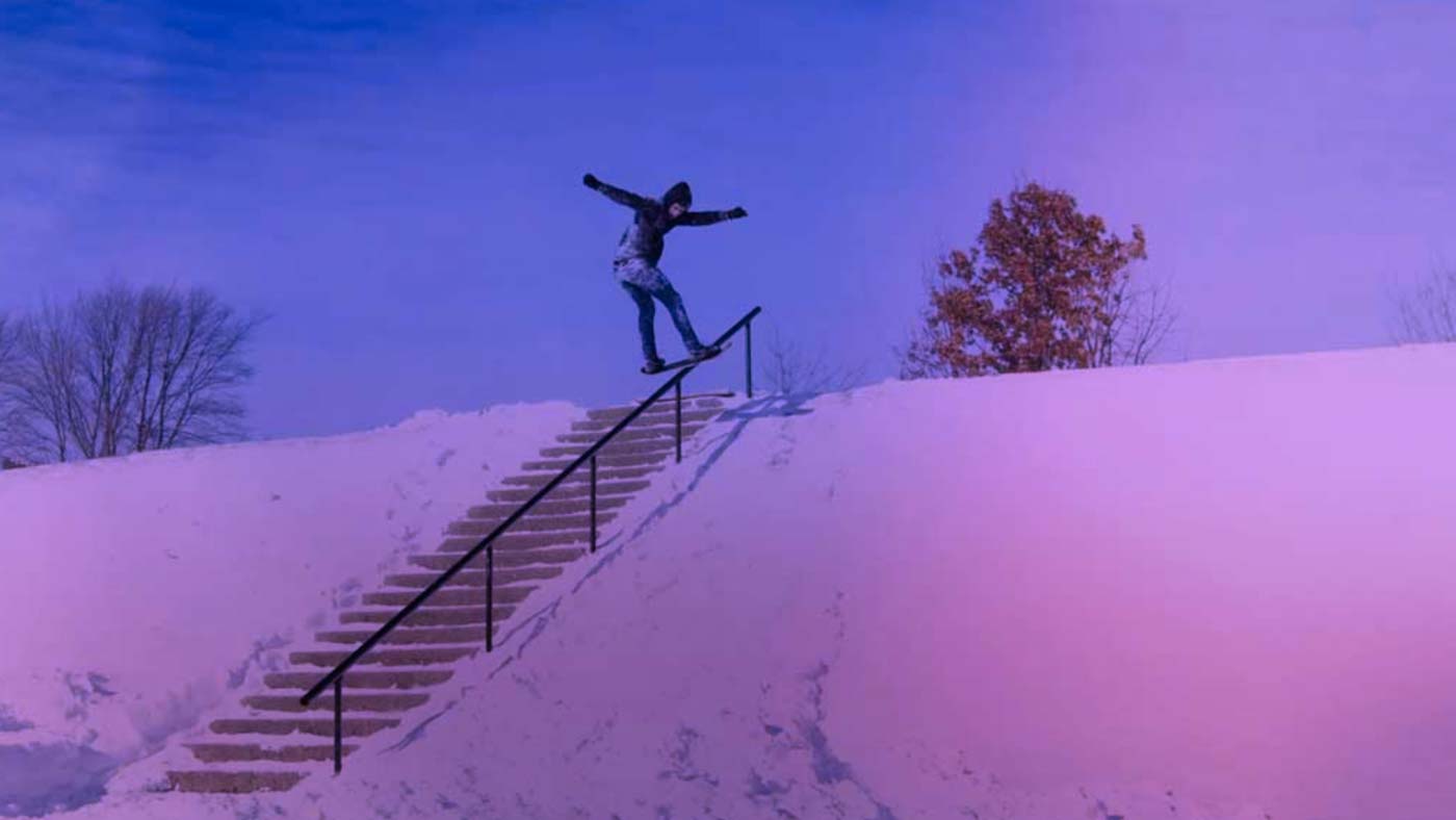 A snowskater hitting a rail in the snow.