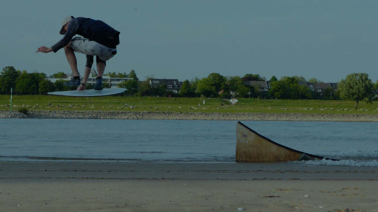 Athklete jumping of the kicker with a skimboard. Flatwater lagoon.