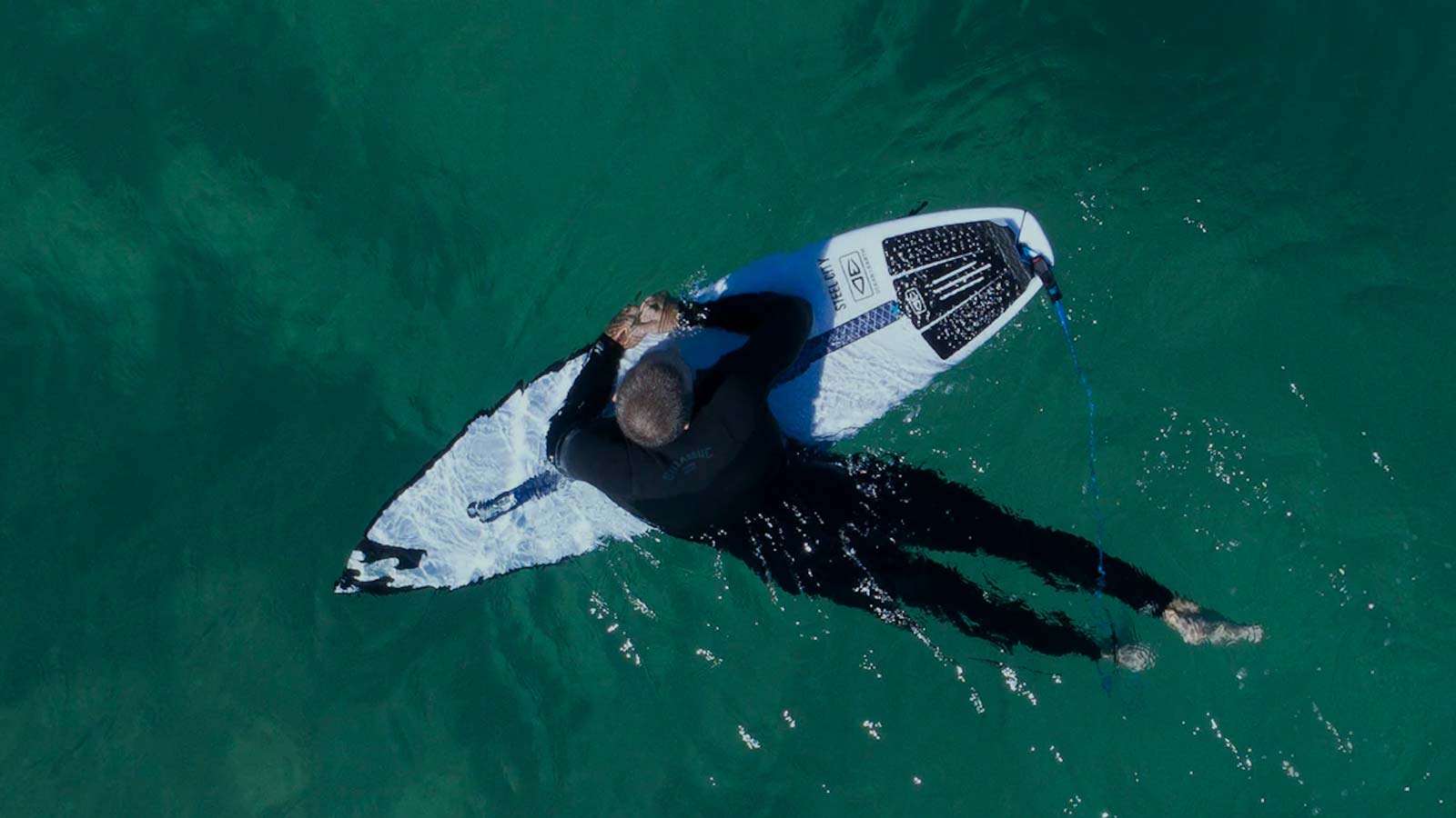 Birds View. Surfboard resting in ocean floating on surfboard. Neoprene wetsuit. Shortboard.