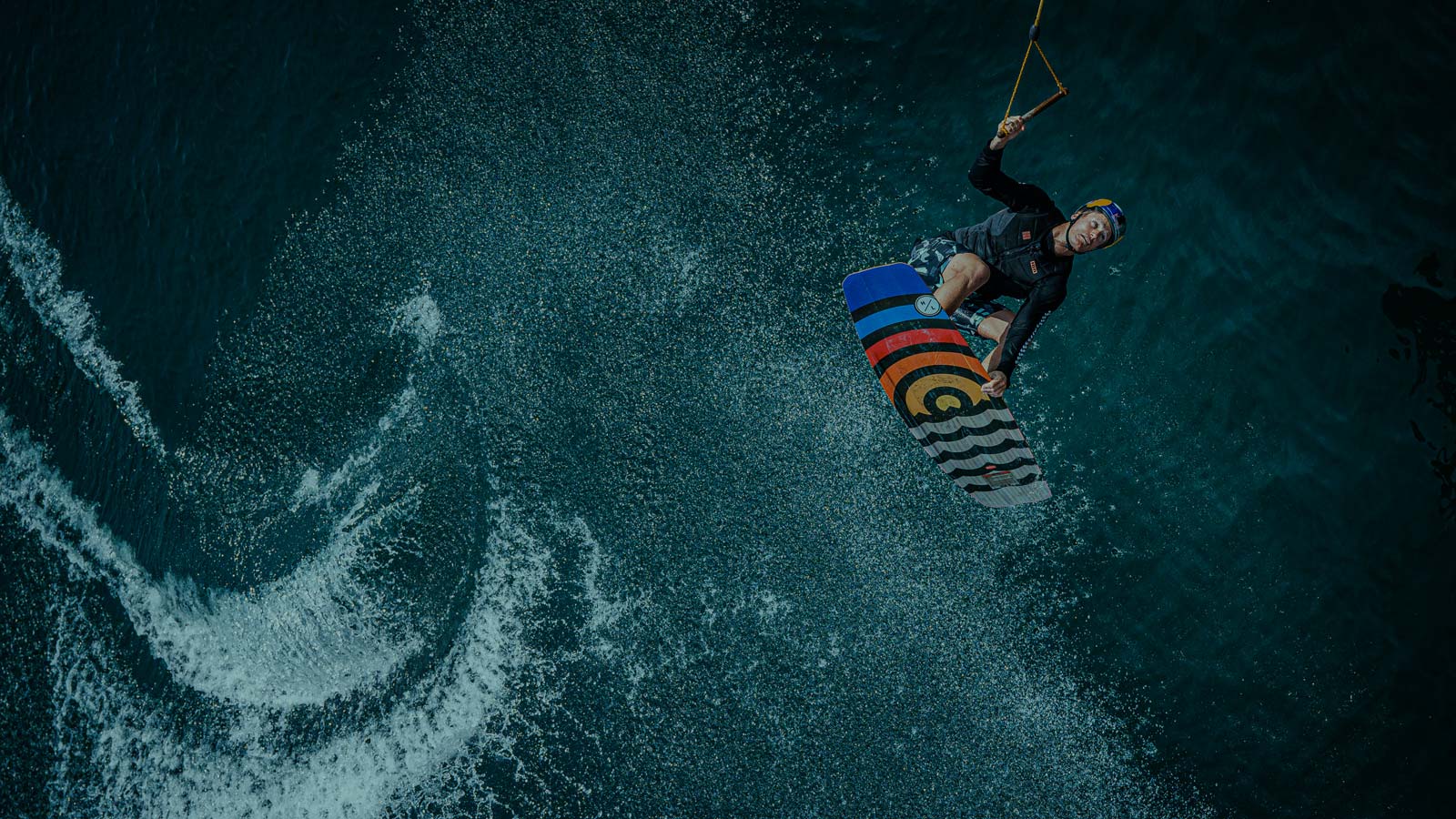 Wakeboarder performing areal trick. Water Splash. Board grab.