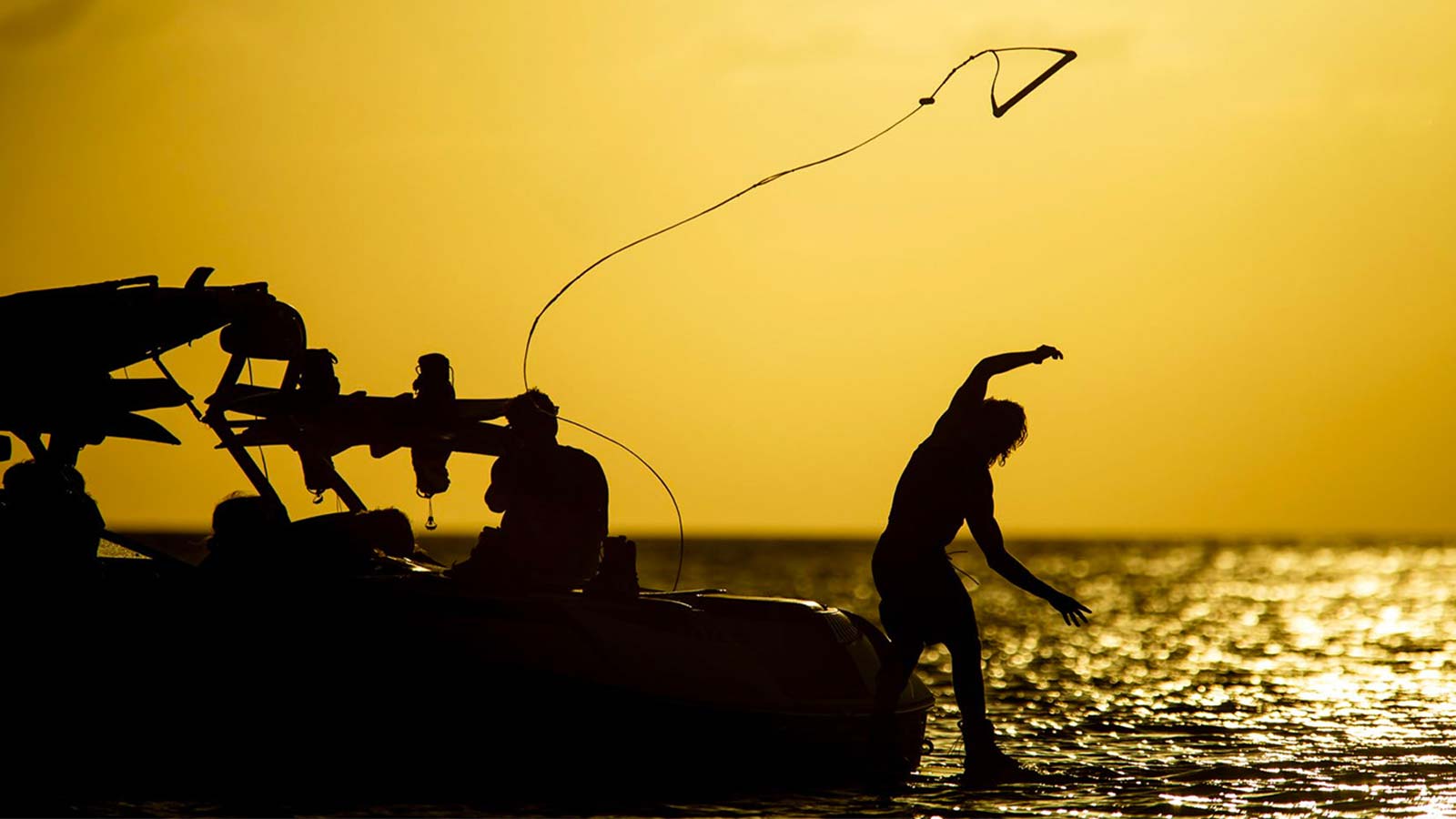 Wakeboard handle gets passed trough the air to the wakeboarder. Sunset. A good handle provides a secure grip, the right diameter for your hands, and materials that stay comfortable even when wet.