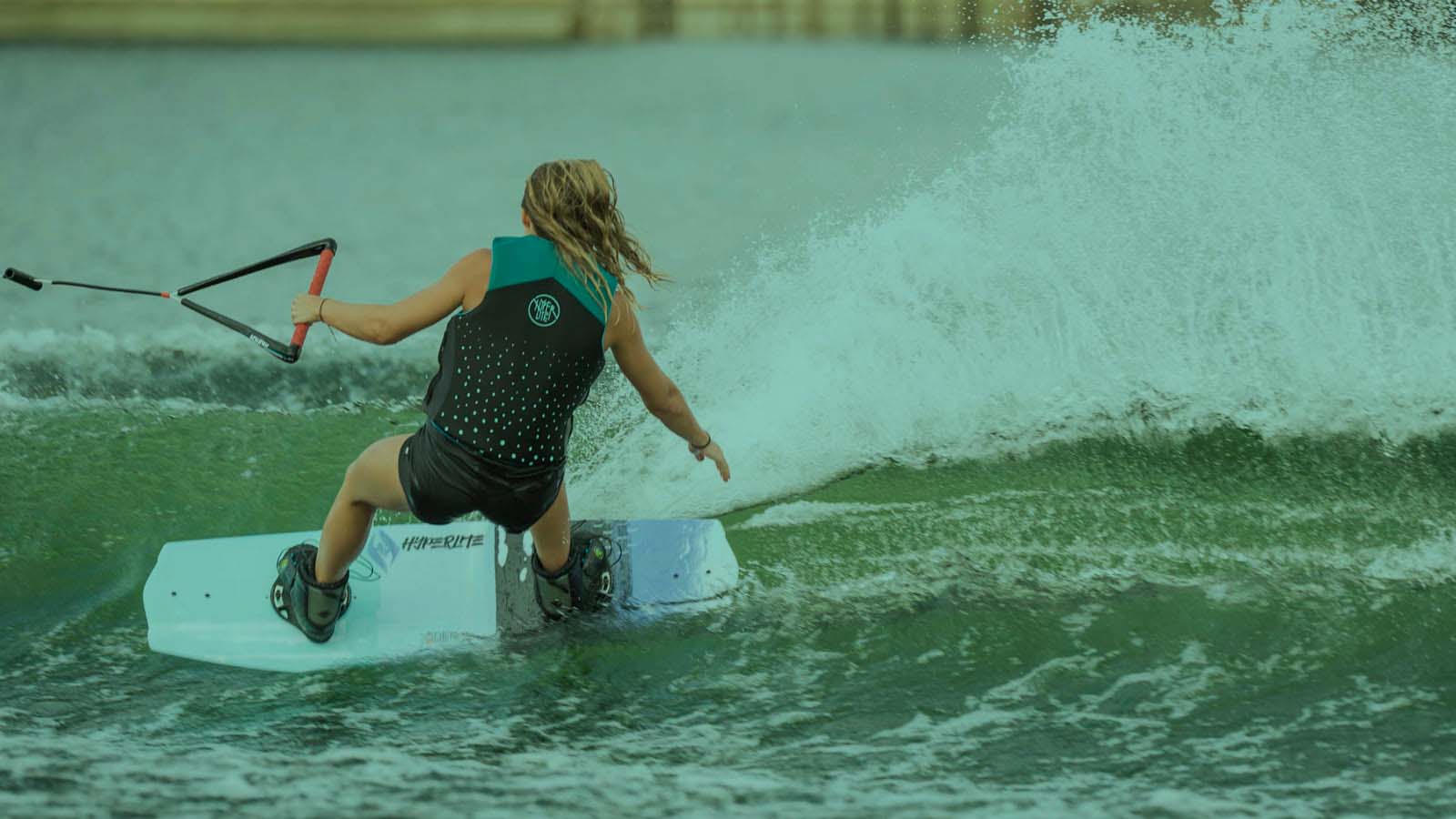 Wakeboarding behind the boat. Speed, wake and wakeboarder cuttoing water trought the wake with a wide splash.