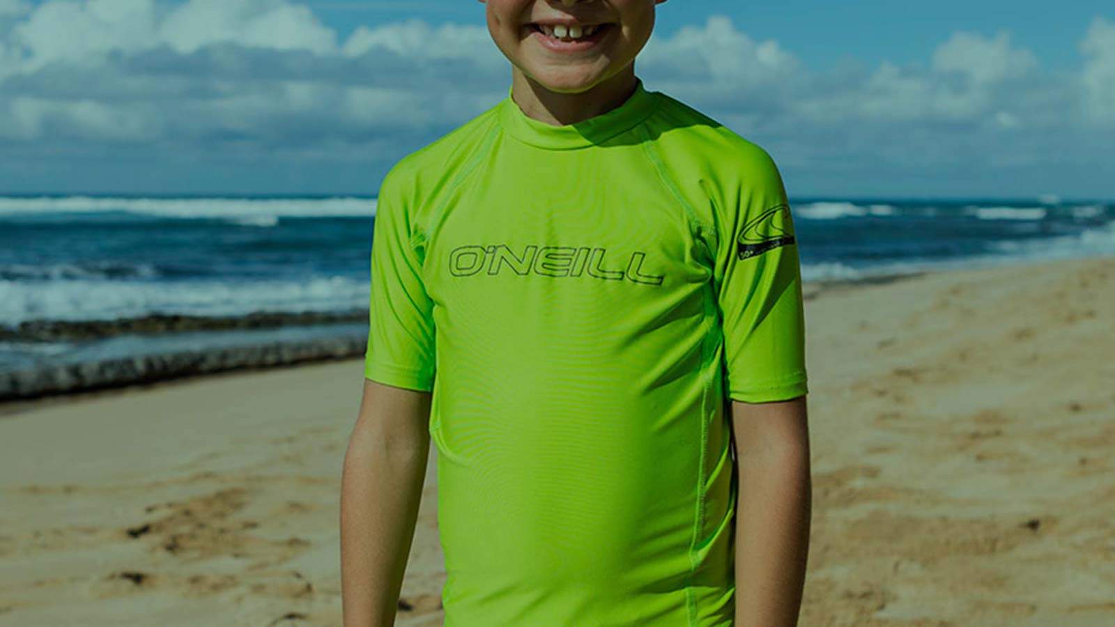 Kid enjoying summer beach day. Stay covered from Harmful UV rays with O'Neill Basic Skins.