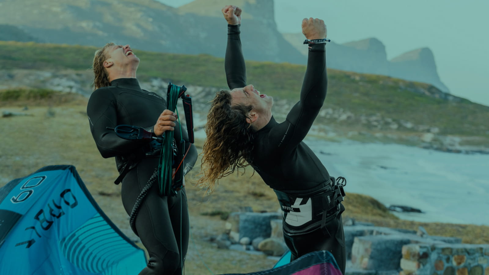 Happy windsurrfer and kitesurfer chearing on the beach.