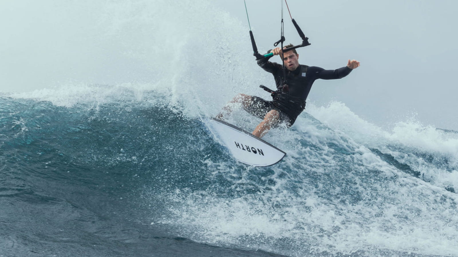 Kiteboarder with a directional surfboar cutting trough the wave.