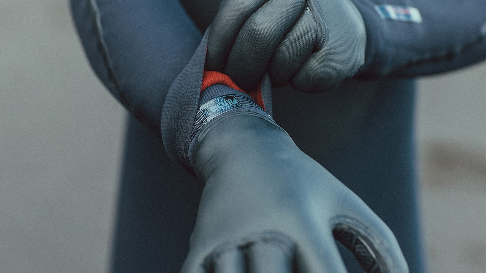 Neoprene gloves. Close-up. Person in wetsuit in the background.