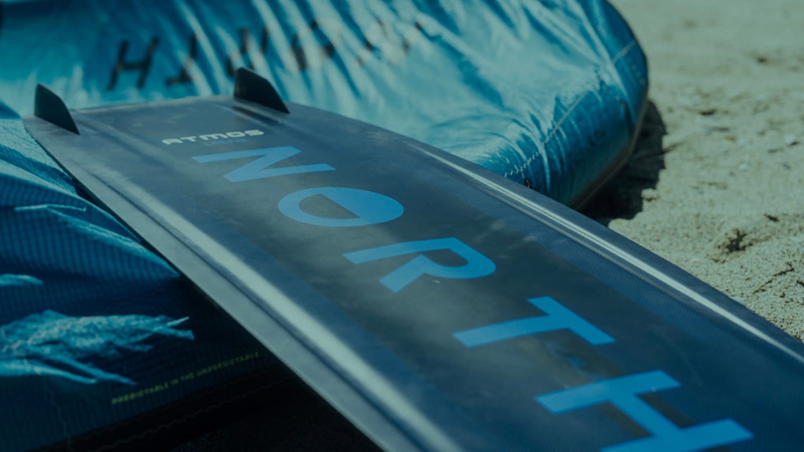Close up kiteboard bottom with fions on top near the pumped kite.jpg