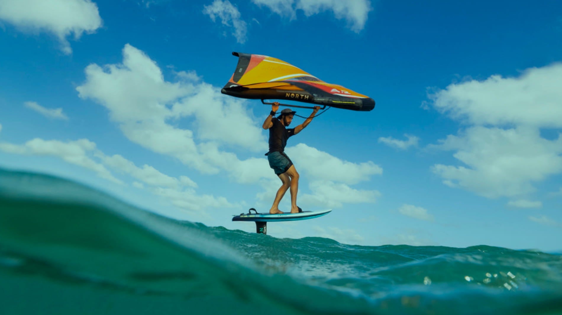 Wingsurfer catching wind and current. Blue sky and turquoise water.